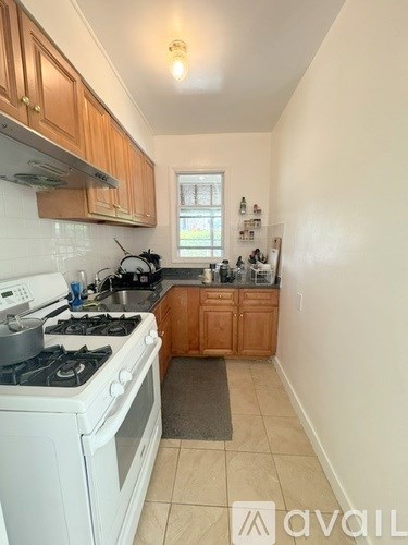 A kitchen with a white stove top oven and wooden cabinets.