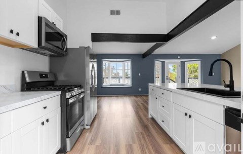 A modern kitchen with white cabinets and a black range hood.