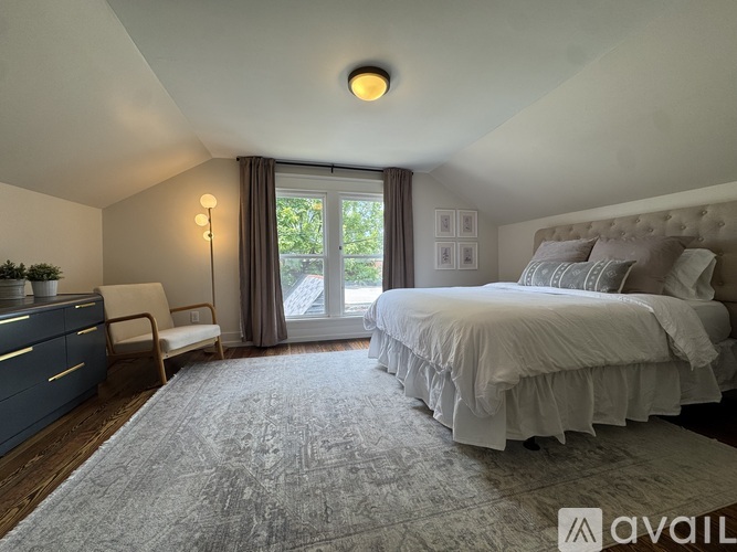 A bedroom with a large bed and a window with curtains.