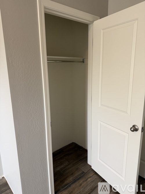 A white door is open to a room with a wooden floor.