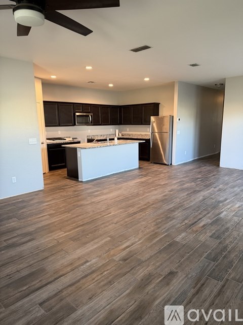 A spacious kitchen with dark wood flooring and a ceiling fan.