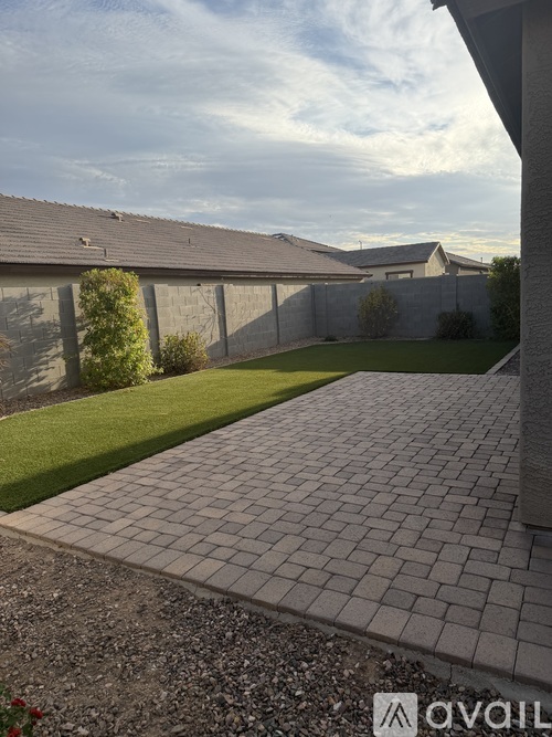 A backyard with a paved walkway leading to a house.