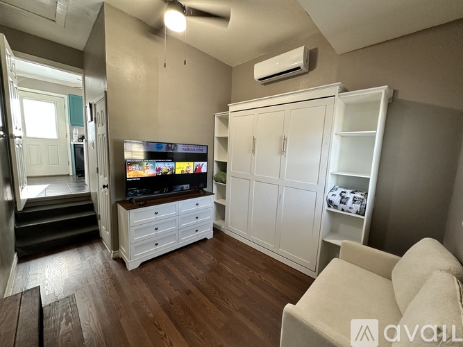 A living room with a television, a couch, and a cabinet.