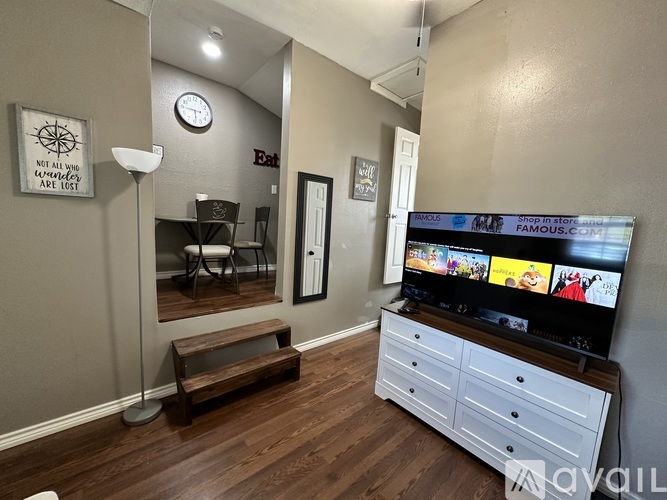 A living room with a flat screen TV and a wooden bench.