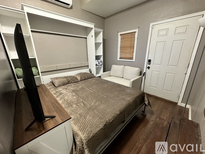 A bedroom with a bed, a TV, and a door.