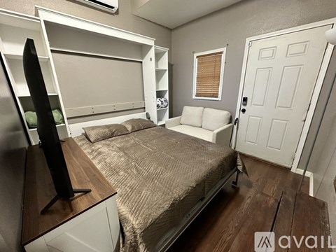 A bedroom with a bed, a TV, and a door.