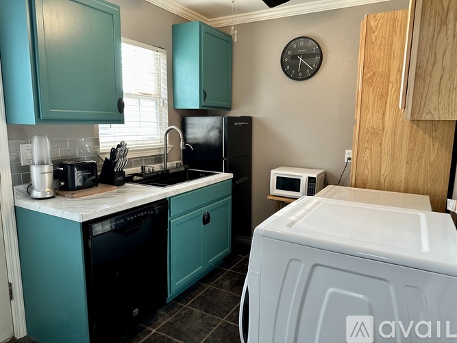 A kitchen with teal cabinets and a black refrigerator.