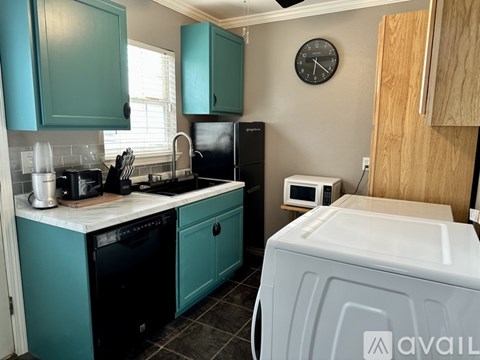 A kitchen with teal cabinets and a black refrigerator.