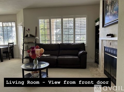 A living room with a black leather couch and a coffee table with flowers on it.