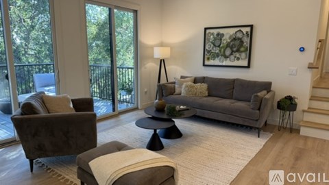 A living room with a grey couch, a chair, a table, and a painting on the wall.