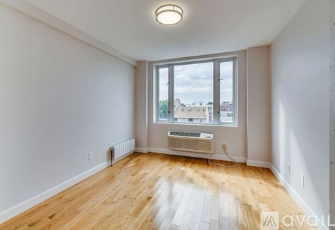 A room with wooden flooring and a large window overlooking a cityscape.