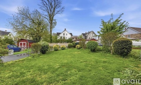 A grassy area with a house and trees in the background.