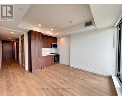 A spacious room with wooden flooring and a kitchen area with a microwave and oven.