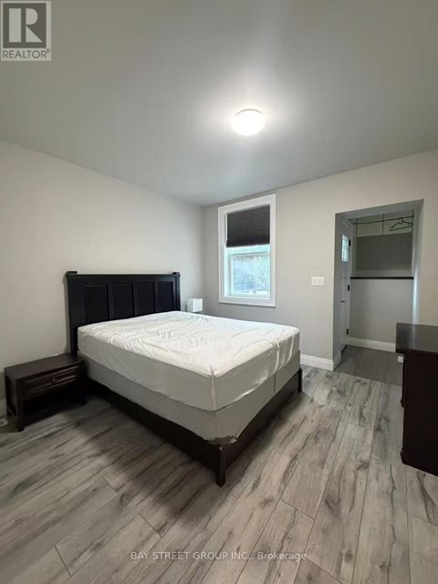 A bedroom with a bed, nightstand, and a window.