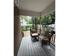 A wooden deck with two chairs and a potted plant.