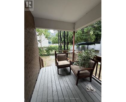 A wooden deck with two chairs and a potted plant.