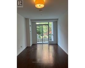 A room with a wooden floor and a sliding glass door leading to a balcony.