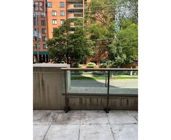 A balcony with a view of a green lawn and trees.