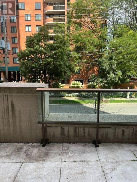 A balcony with a view of a green lawn and trees.