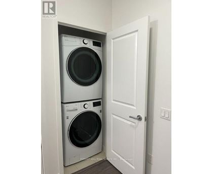 A white door is open to a small laundry room with a washer and dryer.