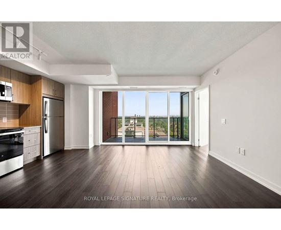 A spacious kitchen with dark wood floors and white walls.