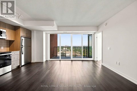 A spacious kitchen with dark wood floors and white walls.