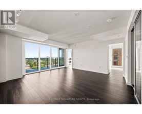 A spacious room with wooden floors and large windows overlooking a body of water.