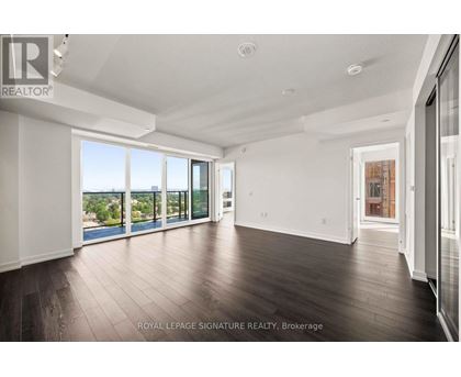 A spacious room with wooden floors and large windows overlooking a body of water.