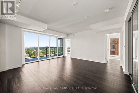A spacious room with wooden floors and large windows overlooking a body of water.