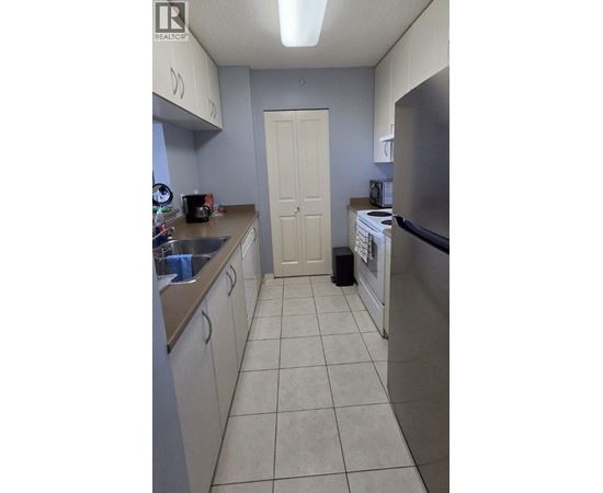A kitchen with a white door and a stainless steel refrigerator.