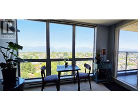 A room with a table and chairs in front of a large window with a view of the mountains.