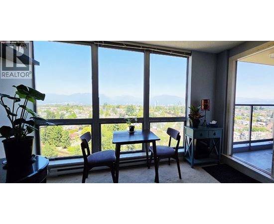 A room with a table and chairs in front of a large window with a view of the mountains.