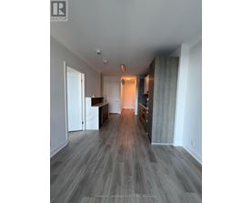 A spacious room with wood flooring and a bar area.