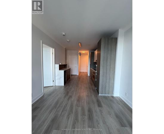 A spacious room with wood flooring and a bar area.
