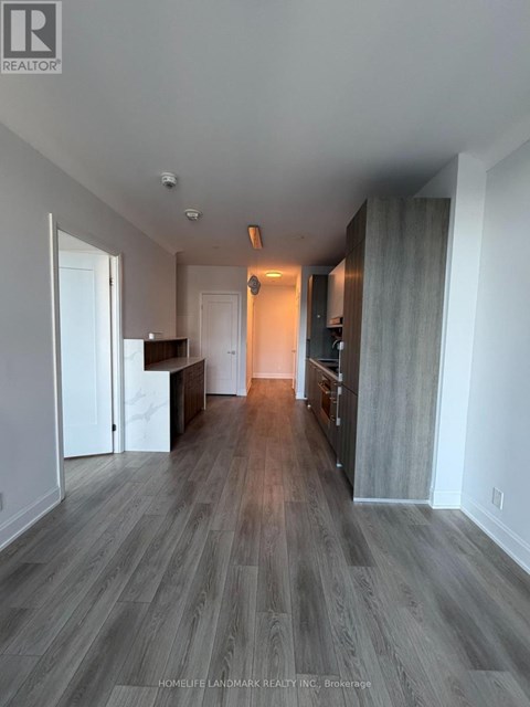 A spacious room with wood flooring and a bar area.