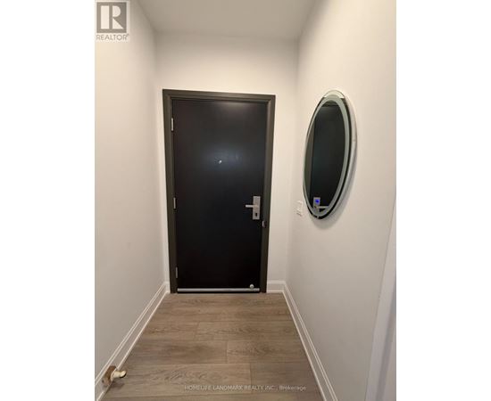 A hallway with a black door and a round mirror on the wall.