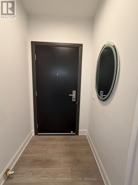 A hallway with a black door and a round mirror on the wall.