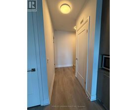 A hallway with a light on the ceiling and a door on the left.