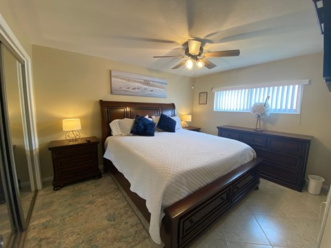A bedroom with a large bed and a ceiling fan.