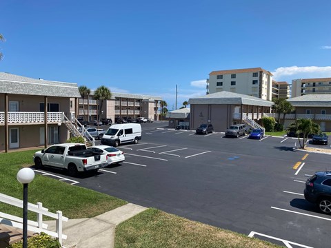 A parking lot with cars and a white picket fence in front of a building.