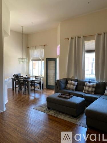 A living room with a grey couch and a dining table.