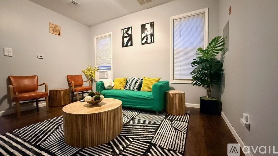 A living room with a green couch, a wooden coffee table, and a striped rug.