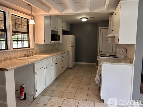 A kitchen with white cabinets and a tiled floor.