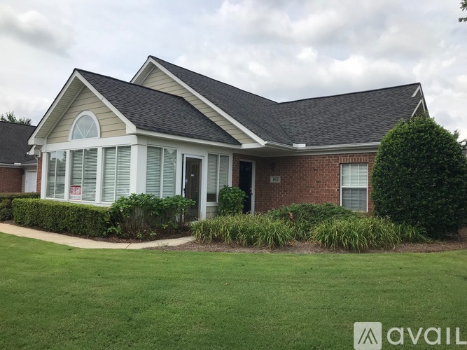 A house with a grey roof and a brick wall is available for sale.