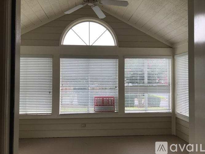 A room with a ceiling fan and a window with blinds.