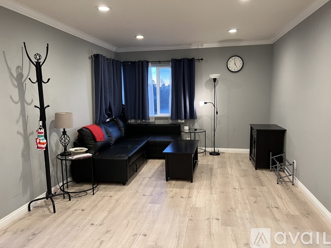 A living room with a black sofa and a wooden floor.