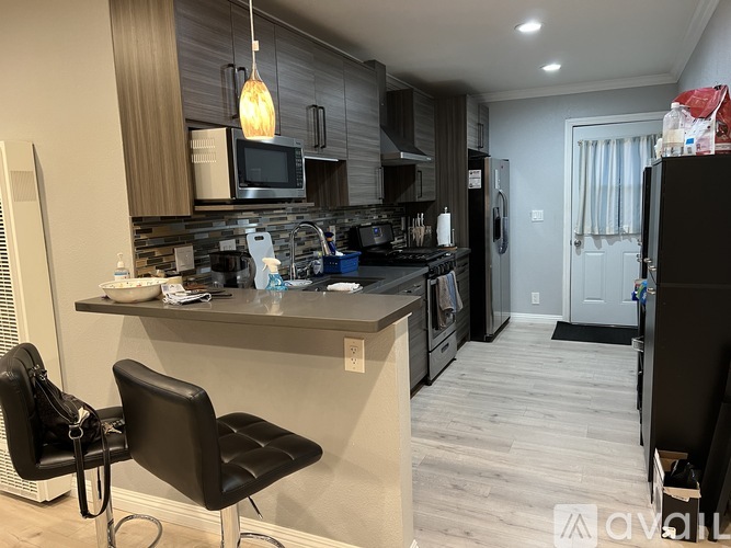 A kitchen with a black chair and a black fridge.