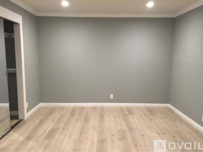 A spacious room with wooden flooring and a grey wall.