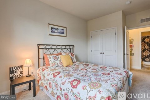 A bedroom with a floral bedspread and a lamp on a side table.