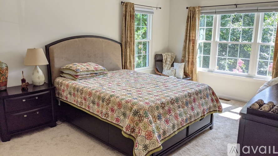 A bedroom with a large bed and a window with curtains.